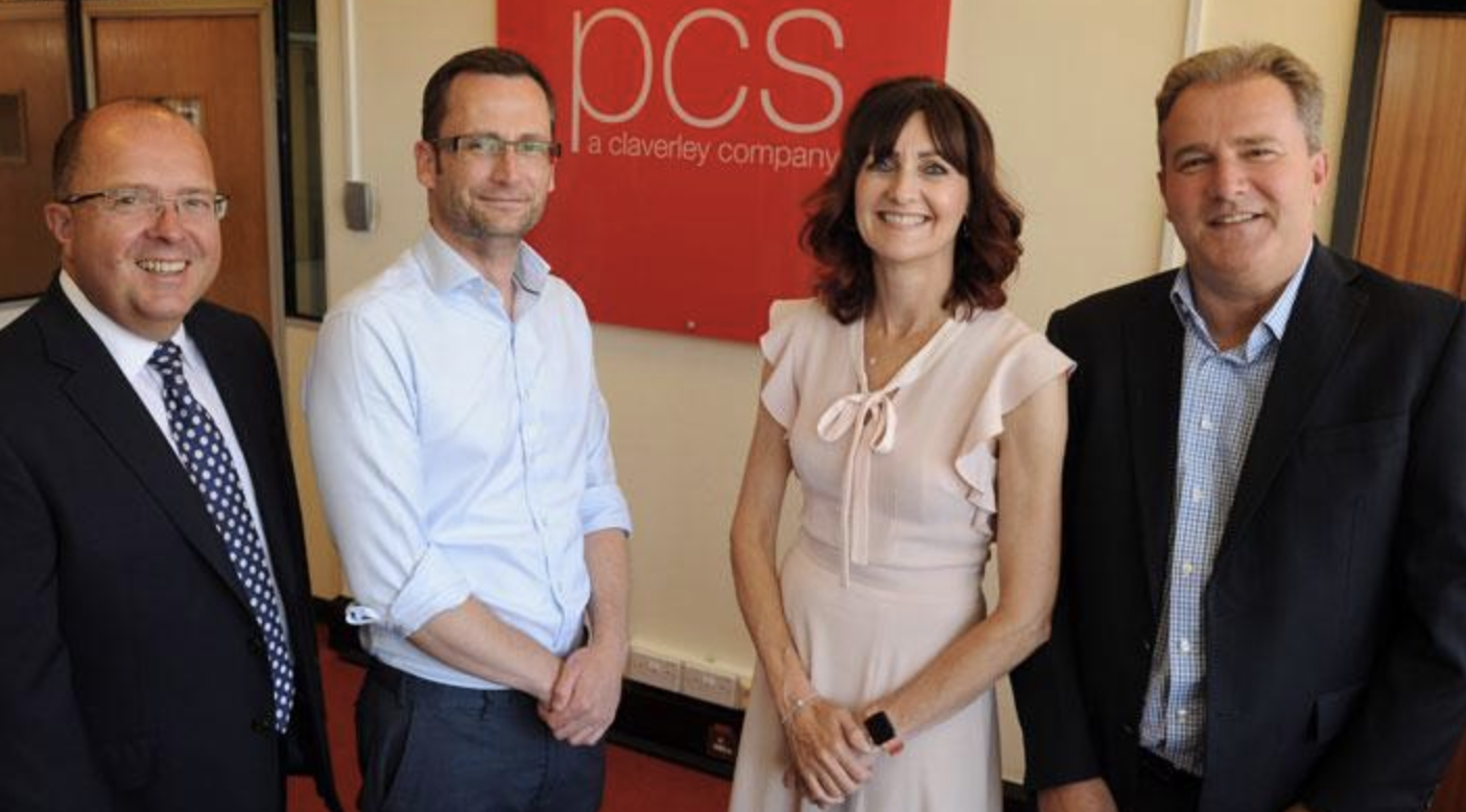 Graeme Clifford, Simon Weare, Louise Burns and Phil Walker in front of a PCS logo